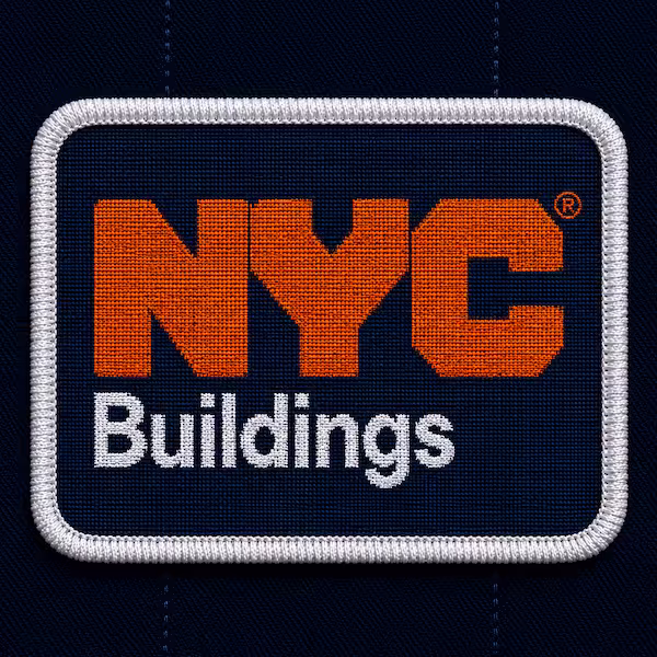 Rectangular dark blue woven patch featuring orange NYC text above white Buildings text with a white border